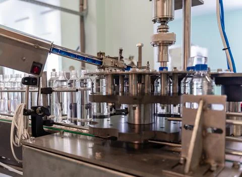The process of twisting the lids on plastic bottles. Water production. Stock Photos