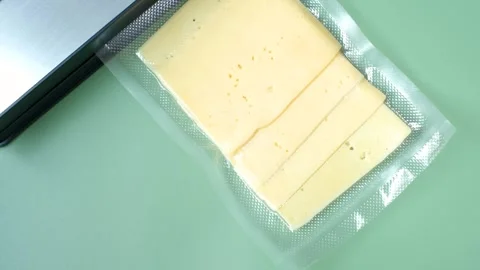 Process of vacuuming pieces of cheese packed in plastic bag on a green Stock Footage 280223070