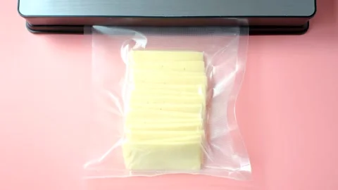 Process of vacuuming pieces of cheese packed in plastic bag on pink background Stock Footage 315646489