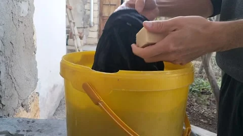 The process of washing by hand by a man using solid laundry soap in a yello.. Stock Footage 266532617