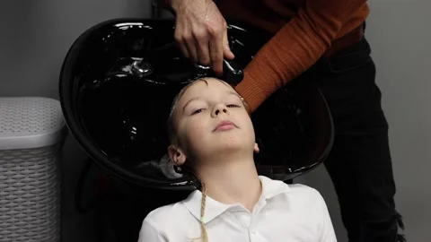 The process of washing head a blond boy in a chair in a barbershop salon, a Stock Footage 146607650