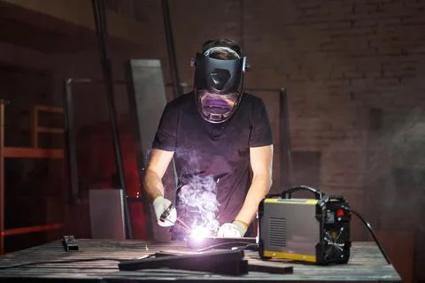 The process of welding two pieces of iron. welder in a black helmet at work Stock Photos