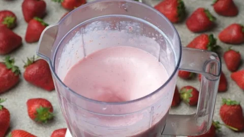 The process of whipping strawberry milkshake in a blender slow motion Stock Footage 311698481