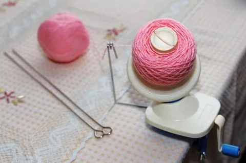 Process of winding pink wool yarn from tangle to winding, using a coiler Stock-Fotos