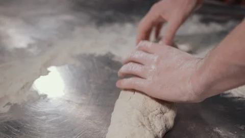 Process of working with dough in flour on stainless steel table by man. Stock-Footage 120592631