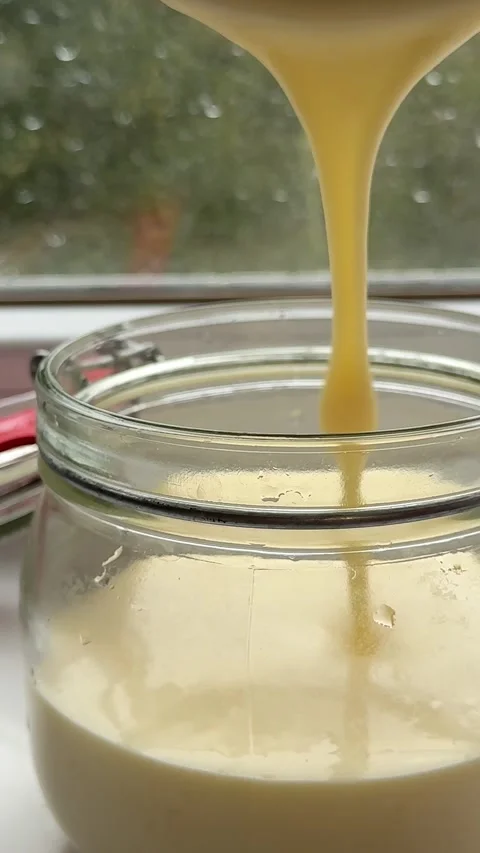 Processed cheese preparation pour into a glass jar, liquid consistency, cheese Stock Footage 323456218