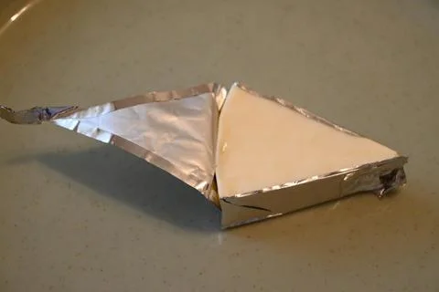 Processed cheese wedge in foil Foto stock
