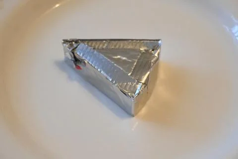 Processed cheese wedge in foil wrapper Stock Photos