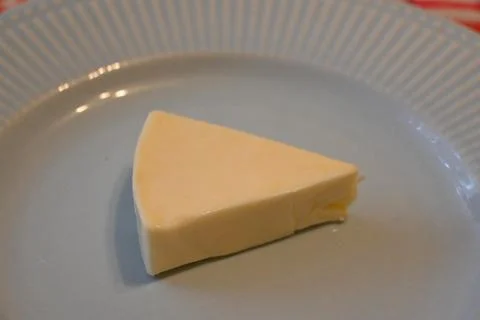Processed cheese wedge on plate Stock Photos