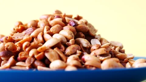 Processed pea nuts on a plate on color background Stock Footage 184481313