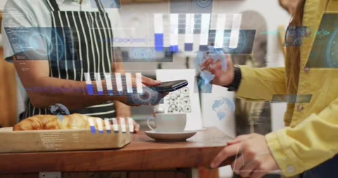 Processing barista in apron holding device while yellow jacket tapping watch Stock Footage 331565384