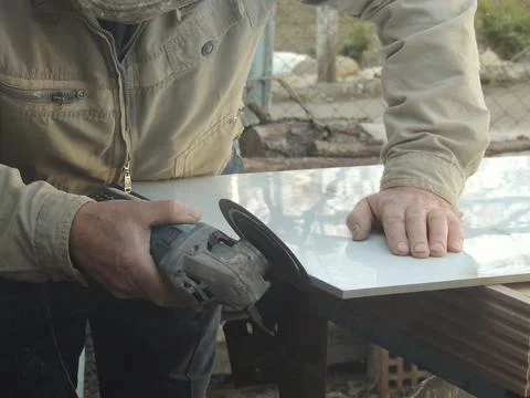 Processing the edge of the facing tile with a grinder Stock Photos
