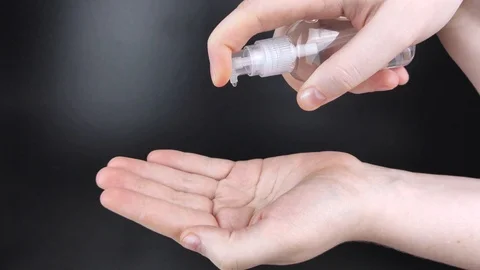 Processing female hands with an antiseptic on a black background. Antibacterial  Stock Footage 125772556