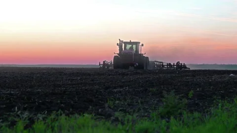 Processing the field with a red tractor, cultivation before planting plants a Stock Footage 165835156