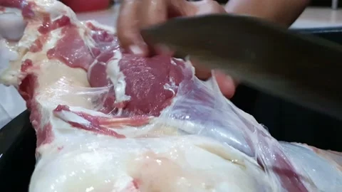 Processing fresh meat. Butcher with a knife in hand slicing meat, person work Stock Footage 145820539