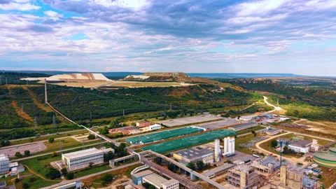 Processing plant below terraced quarry mounds and layered clouds. Aerial 库存影片 339367917