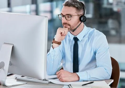 Processing the situation. a mature call centre agent working on a computer in an Stock Photos