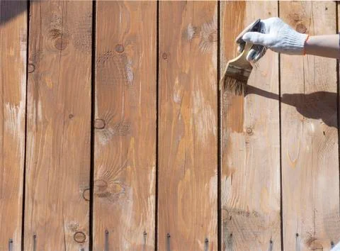 Processing of the wooden wall outside.A man's hand in a glove paint the woode Stock Photos