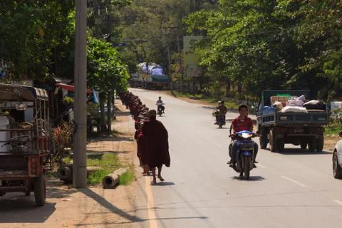 Procession of buddhist monks walks down the street to collect offerings Stock Photos