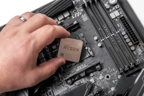 Processor Ryzen 7 2700X in hand against the background of a computer motherboard Stock Photos