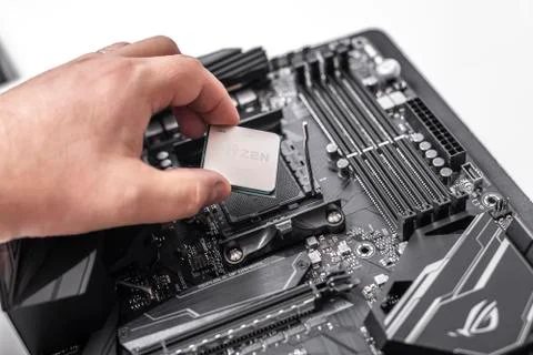 Processor Ryzen 7 2700X in hand against the background of a computer motherboard Stock Photos