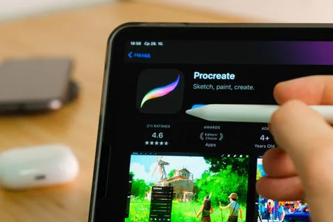 Procreate logo shown by apple pencil on the iPad Pro tablet screen. Man using Stock Photos
