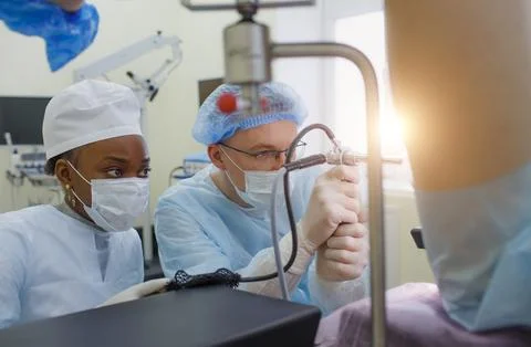 A proctologist with an assistant performs an operation on a patient lying o.. Stock Photos