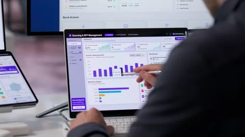 Procurement Manager Analyzes Software On Dual Screen Laptop Vídeo Stock 342962977