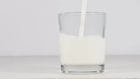 Product close-up milk poured into the drinking glass white white background food Vídeo Stock 336576896