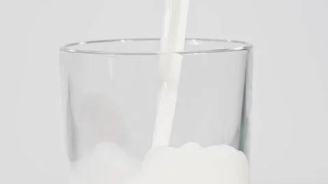 Product close-up milk poured into the drinking glass white white background food Stock Footage 336576897