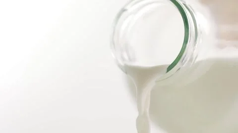 Product close-up milk poured into the drinking glass white white background food Stock Footage 336576904