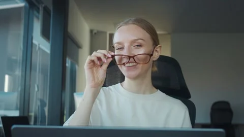 Product manager with eyeglasses smiles while adjusting her glasses and working Stock Footage 312120642