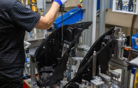 Production operator assembling frontlight headlamp, headlight for a vehicle or a Stock Photos