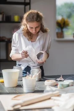 Production process of pottery. Application of glaze brush on ceramic ware. Stock Photos