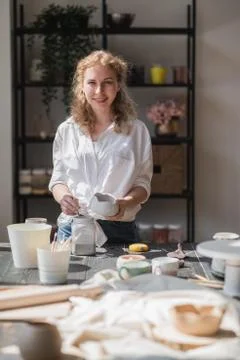 Production process of pottery. Application of glaze brush on ceramic ware. Stock Photos