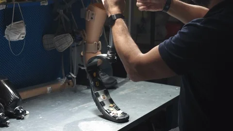 Production of a prosthetic leg. A man creates part of the leg. An engineer is 스톡 동영상 120152273