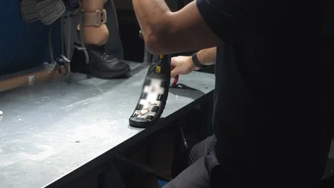 Production of a prosthetic leg. A man creates part of the leg. An engineer is 스톡 동영상 120153079