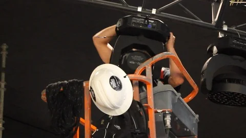Production technician installing large moving head wash light Stock Footage 115452890