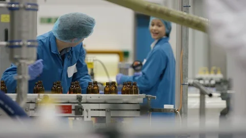Production worker and technician checking cosmetic bottles on production line Video stock 107971317