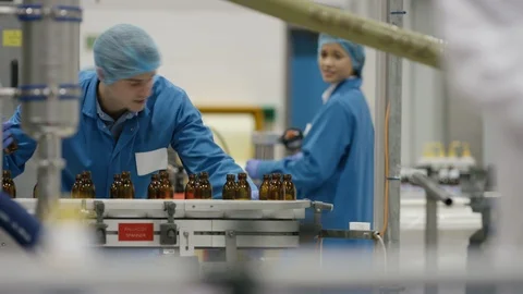 Production worker and technician checking cosmetic bottles on production line Stock Footage 107971843