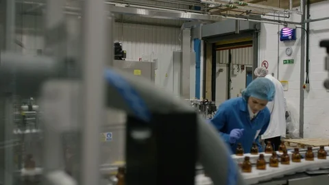 Production worker examining bottles on production line in cosmetic factory Stock Footage 107949587