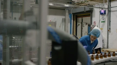 Production worker examining bottles on production line in cosmetic factory Video stock 107949645