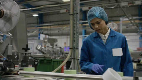 Production worker inspecting packed cosmetic boxes on conveyor belt in factory Stock Footage 107957732