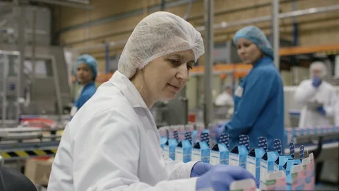 Production worker placing spoon in cosmetic boxes on production line Stock Footage 107956236