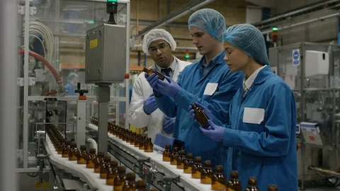 Production workers checking bottles on production line in factory Stock Footage 107953521