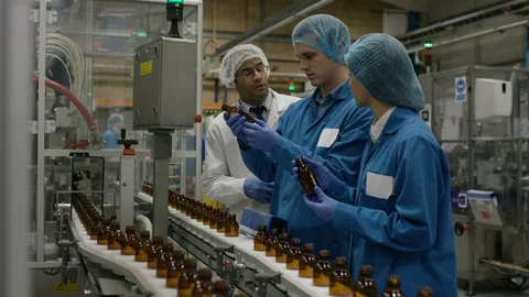 Production workers checking bottles on production line in factory Stock Footage 107953687