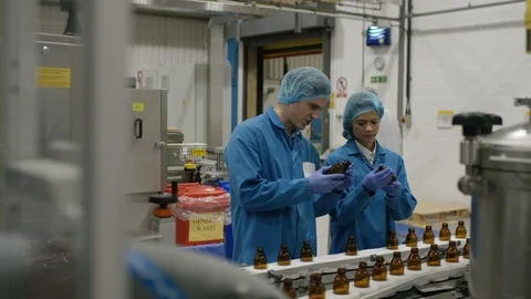 Production workers checking bottles on production line in factory Stock Footage 107953902