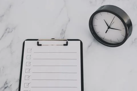 Productivity and deadlines, to do list on clipboard next to big clock on busi Stock Photos