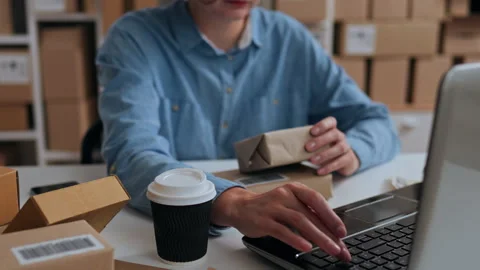 Productivity, Warehouse worker Joyfully Works at a laptop in a packaging war Stock Footage 242533364