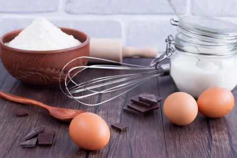 Products and objects for baking chocolate cake on dark wooden table. Concept Stock Photos